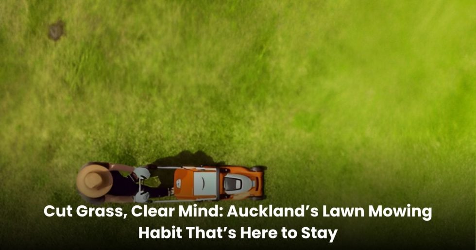 A person mowing a bright green lawn in Auckland using an orange push mower, viewed from above.