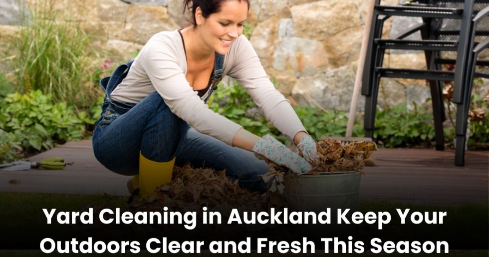 Smiling woman collecting dry leaves during yard cleaning in Auckland backyard.